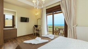 Ein Hotelzimmer mit Bett, Schreibtisch, Stuhl, Fernseher und Meerblick.