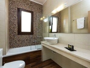 A modern bathroom with a mosaic tile wall, a bathtub, a sink, and a mirror. - Novel Villa in Roupes with Private Pool near Arkadi Monastery (Rethymno)