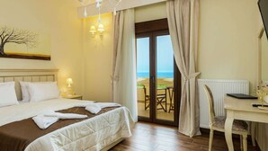 A hotel room with a bed, a desk, a chair, a laptop, and a view of the beach through the door. - Novel Villa in Roupes with Private Pool near Arkadi Monastery (Rethymno)