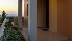 A modern building with a balcony overlooking a scenic view. - Novel Villa in Roupes with Private Pool near Arkadi Monastery (Rethymno)