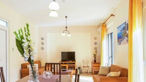 Ein modernes Wohnzimmer mit Essbereich, einem Flachbildfernseher und einer Couch.