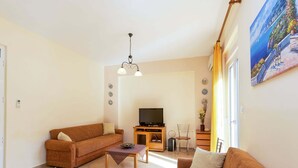 Ein Wohnzimmer mit einer Couch, einem Couchtisch, einer TV-Konsole und einem Bild an der Wand.