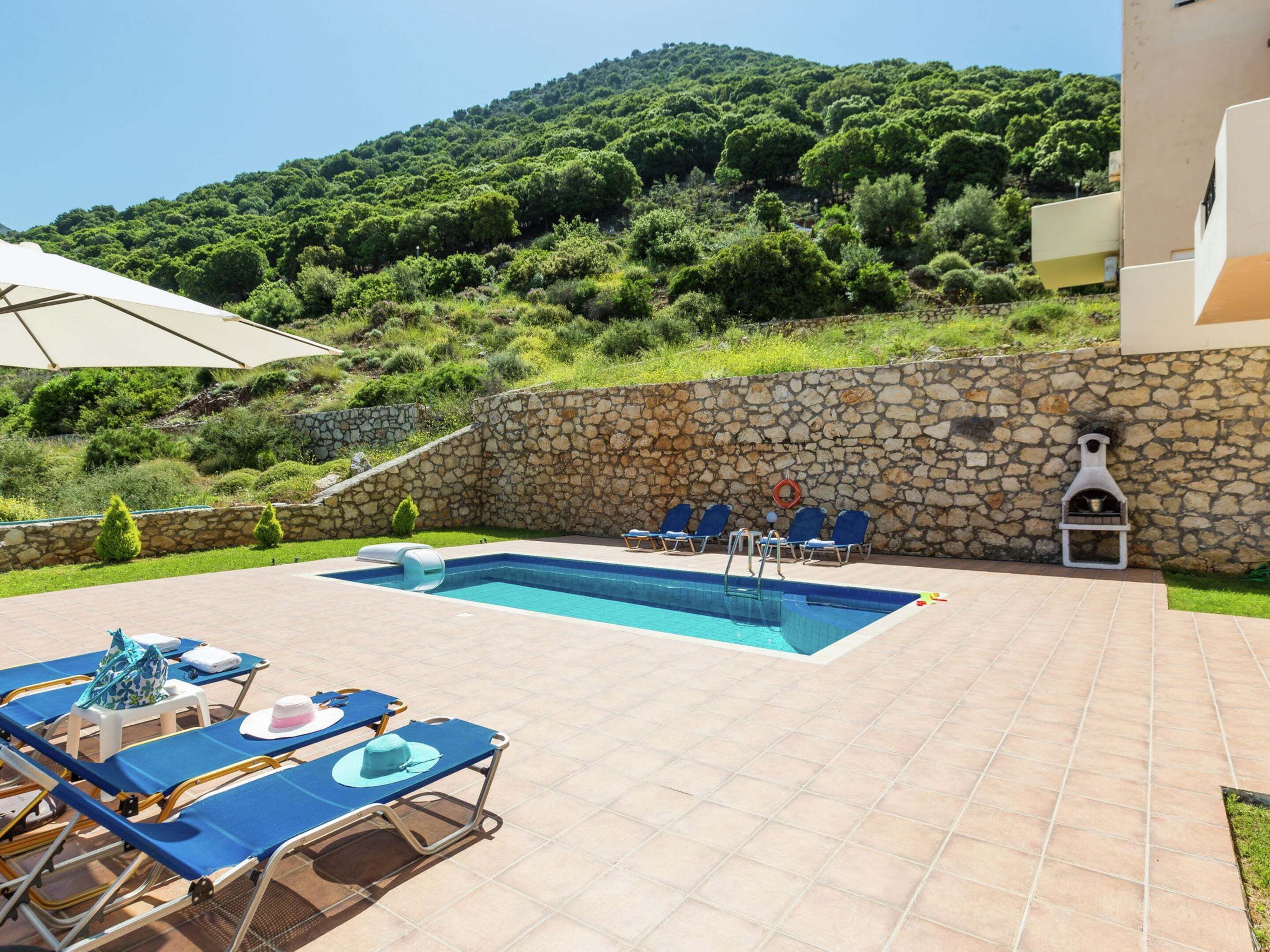 A swimming pool with lounge chairs and a stone wall.