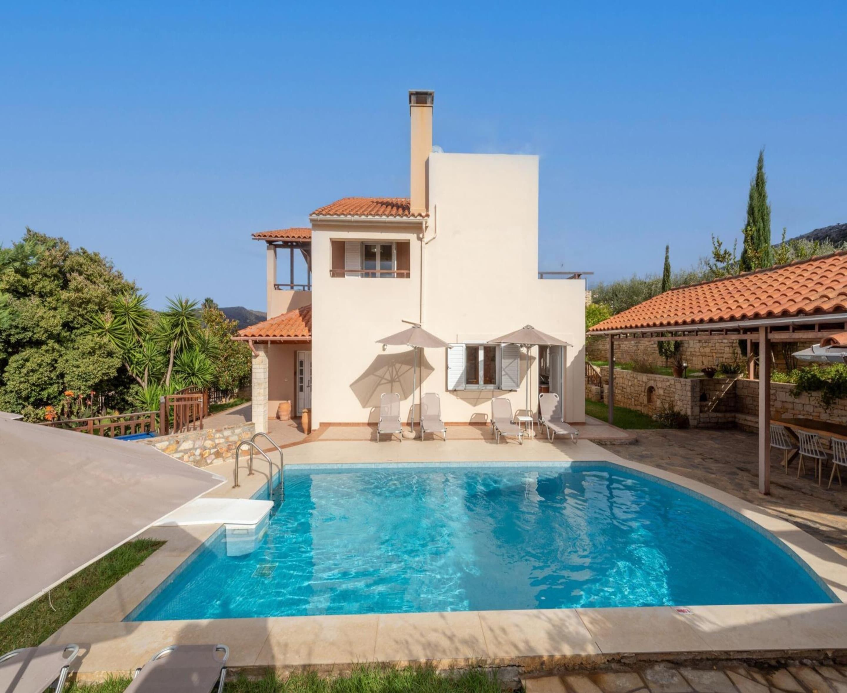 A modern house with a swimming pool, outdoor seating, and a stone wall.