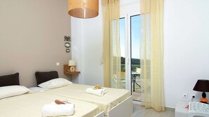 Een slaapkamer met een bed, een nachtkastje met lamp, een raam met gordijnen en uitzicht op de omgeving.