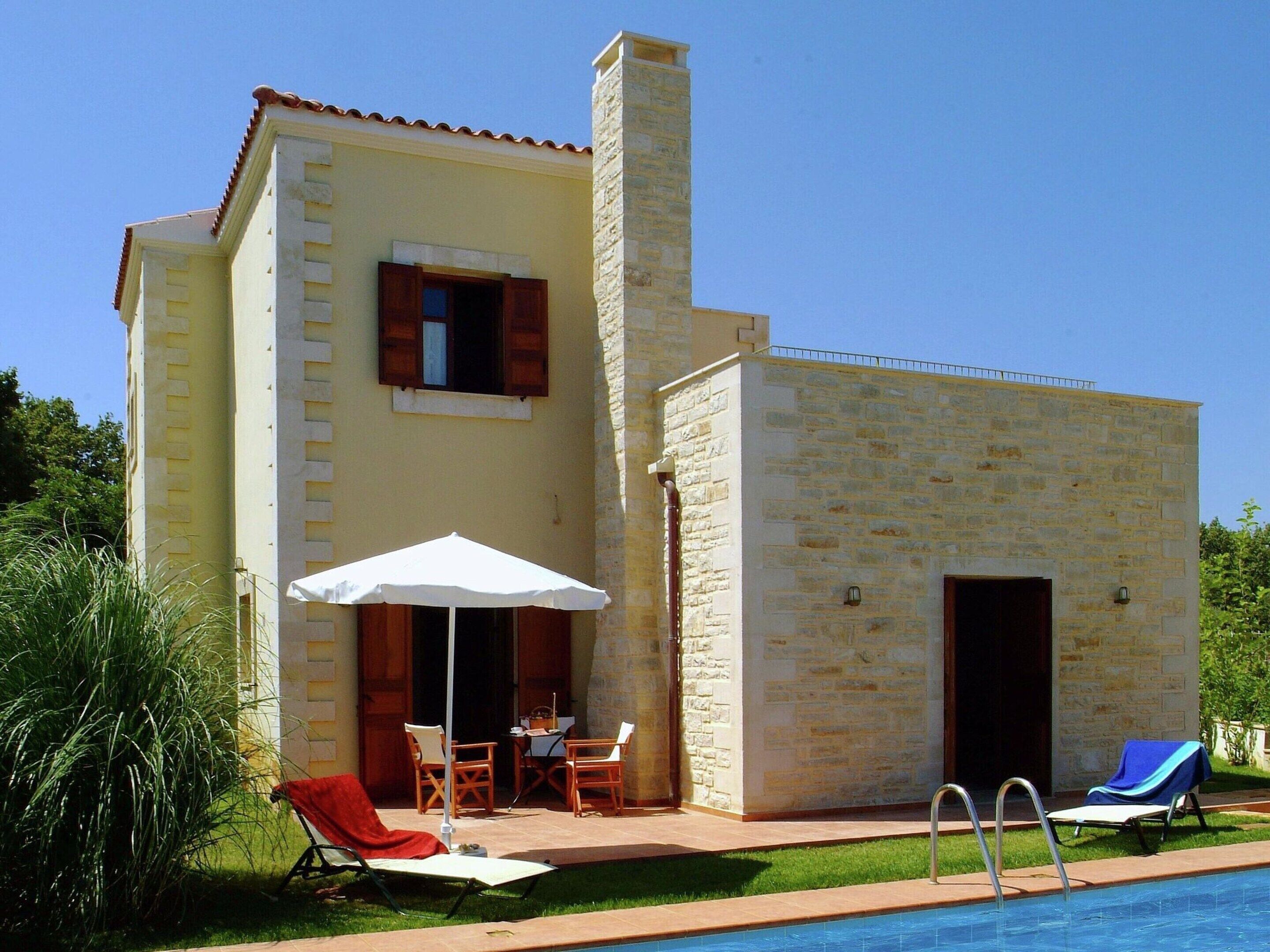 A building with a pool, outdoor seating, and a stone facade.