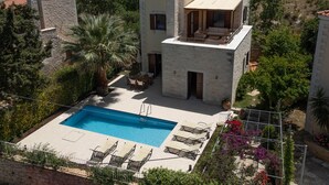 Ein zweistöckiges Haus mit Swimmingpool, Sitzgelegenheiten im Freien und einer Stein-Fassade.