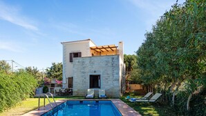 Ein modernes Steinhaus mit Pool und Außensitzgelegenheiten.