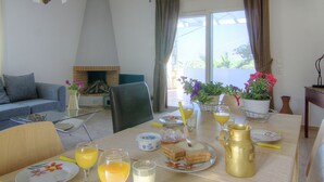 A dining area with a table set for breakfast, including plates, glasses, and a pitcher. - Spacious Villa in Arkadi with Swimming Pool near Sea (Rethymno)