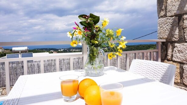 A table with a pitcher of flowers, two glasses of orange juice, and oranges on a balcony overlooking a scenic view. - Spacious Villa in Arkadi with Swimming Pool near Sea (Rethymno)
