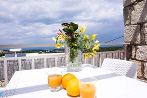 A table with a pitcher of flowers, two glasses of orange juice, and oranges on a balcony overlooking a scenic view. - Spacious Villa in Arkadi with Swimming Pool near Sea (Rethymno)