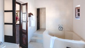 A bathroom with a bathtub, a sink, and a mirror. - Extravagant Villa in Megalochori (Santorini)