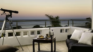 A balcony with a telescope, a dining table with food and drinks, and a sofa with pillows. - Villa on Island With Private Pool (Rhodes)