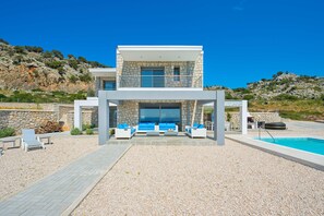 A modern two-story house with a stone facade, a pool, and outdoor seating. - Villa in Rhodes With Infinity Pool & Sea Views (Rhodes)