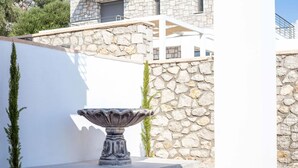 A stone wall with a white structure and a stone fountain in a courtyard. - Villa in Rhodes With Infinity Pool & BBQ (Rhodes)