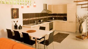 A modern kitchen with a dining area, featuring a white table, black chairs, and a spiral staircase.