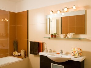 Ein modernes Badezimmer mit Badewanne, Waschbecken, Spiegel und Ablagefläche mit Dekoration.
