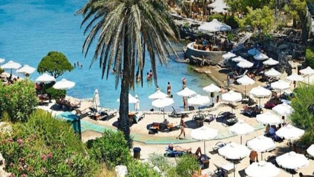 Ein Resort mit Poolanlage, umgeben von Palmen und Sonnenschirmen, mit badenden und entspannenden Personen.