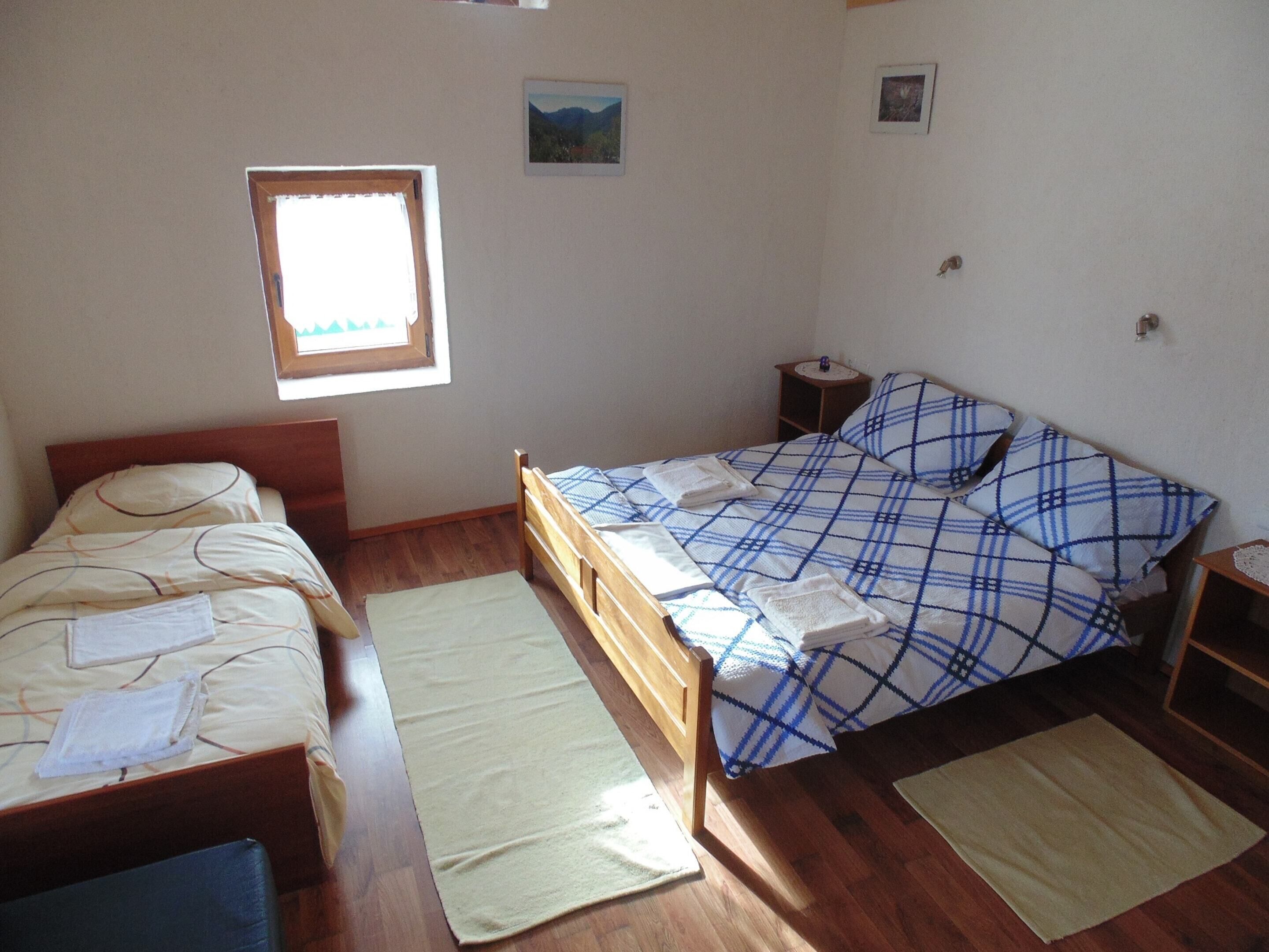 A room with two beds, a window, and a small bedside table.