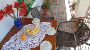 Uma mesa de madeira com toalha rendada, um vaso com flores vermelhas e uma bandeja de frutas.