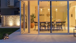 Een modern huis met een glazen deur die leidt naar een eetgedeelte met een tafel en stoelen.