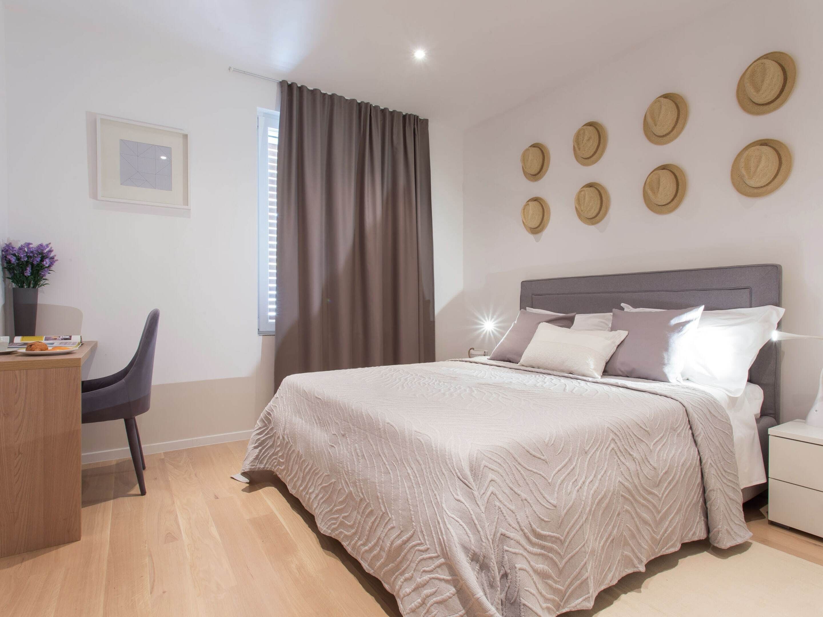 Un dormitorio moderno con cama, mesita de noche y escritorio con silla.