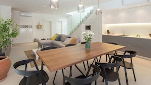 Een moderne keuken met een houten eettafel, zwarte stoelen en hanglampen.