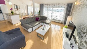 A modern living room with a grey sectional sofa, a white coffee table, and a TV stand with a flat-screen TV and sound system. - Luxurious Villa in Dalmatia Near Sea (Nin)