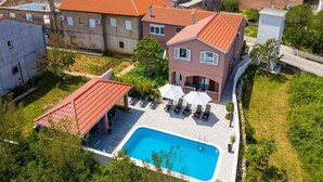 A residential area with a swimming pool, a covered patio, and a row of houses with red-tiled roofs. - Luxurious Villa in Dalmatia Near Sea (Nin)