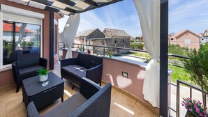 A balcony with wicker furniture, a table, and a potted plant. - Luxurious Villa in Dalmatia Near Sea (Nin)