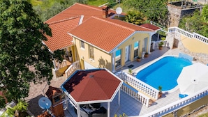 A two-story house with a swimming pool, a covered patio, and a satellite dish.