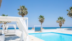 A poolside area with a clear view of the sea, white lounge chairs, and palm trees. - Luxury Villa, Private Pool & Beach, Pigianos Kampos, Rethymno Area, NW Coast (Rethymno)