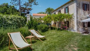 A villa with a well-maintained lawn, two lounge chairs, and a stone building with a tiled roof. - Holiday Home in Osor Near Sandy Beach (Mali Losinj)