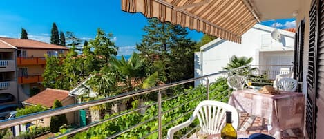 Un balcone con tavolo, sedie, una bottiglia e un libro.