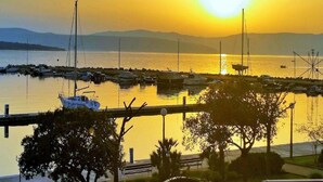 Un puerto deportivo con barcos amarrados, un puente y un atardecer sobre el agua.