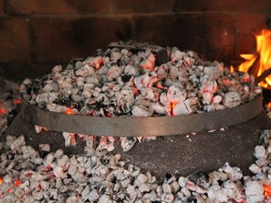 A circular charcoal grill with burning coals and a fire burning in the background. - Holiday Home in Zemunik Donji With Pool (Zemunik Donji)