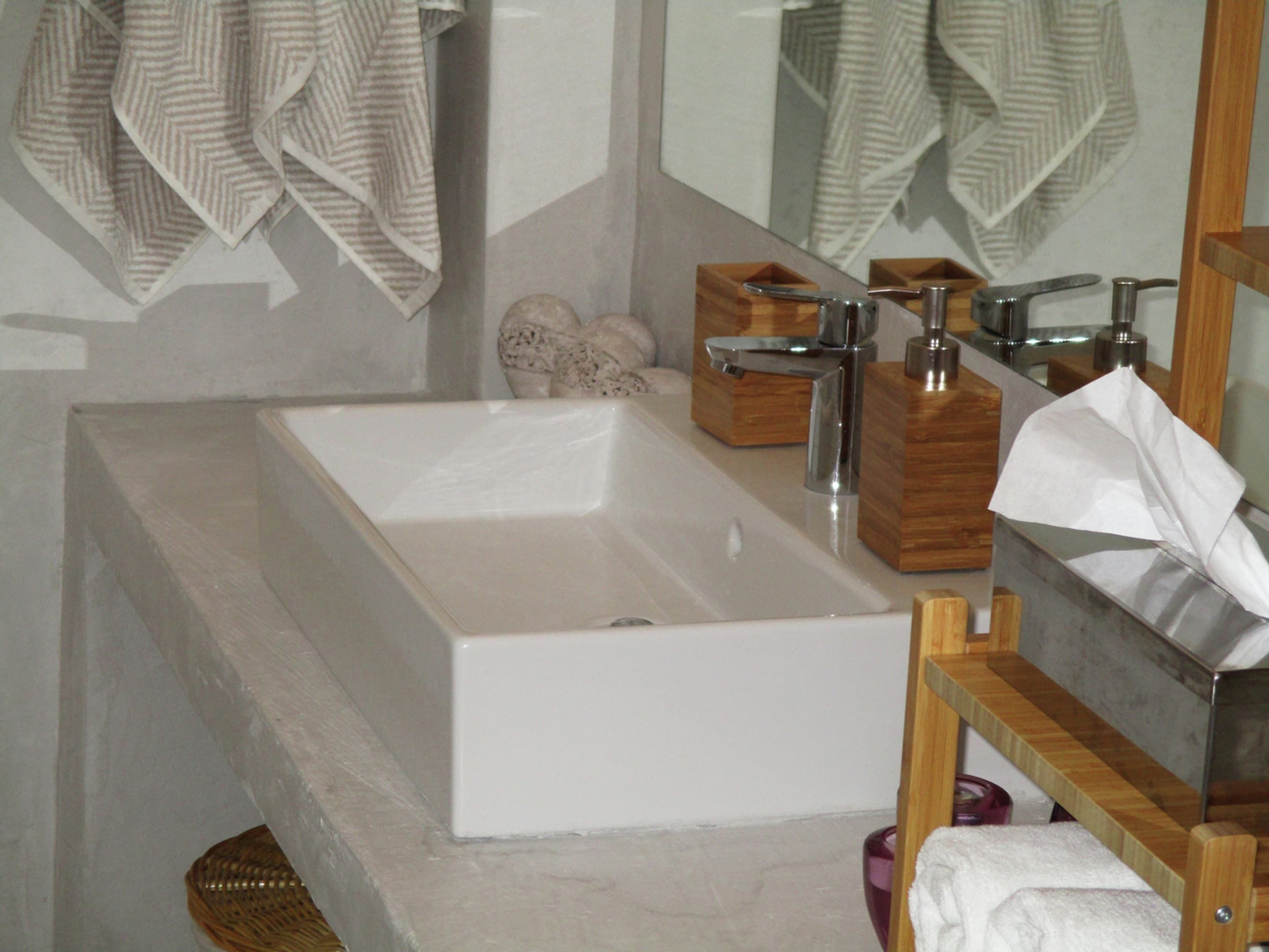 A modern bathroom with a large rectangular sink, wooden storage boxes, and a mirror.