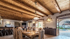 A wooden dining area with a high ceiling and exposed beams, a brick fireplace, and a view of the outside through an arched doorway. - Villa in Sukosan With Pool Near the Sea (Sukosan)