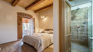 A bedroom with a wooden ceiling, a bed with a beige duvet, a brick wall, and a wooden door. - Villa in Sukosan With Pool Near the Sea (Sukosan)