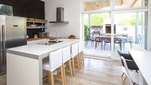 Una cucina moderna con isola centrale, elettrodomestici in acciaio inossidabile e zona pranzo con vista su un giardino.