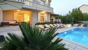 Una moderna casa a due piani con piscina, area salotto esterna e patio coperto.
