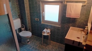 Ein Badezimmer mit Toilette, Waschbecken und Fenster.
