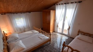 Une chambre avec deux lits en bois, une armoire et une fenêtre avec des rideaux.