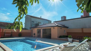 A swimming pool with lounge chairs and a building in the background. - Holiday Home in Imotski With Pool (Imotski)