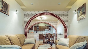 A living room with two sofas, a coffee table, and a kitchen visible through an arched brick wall. - Holiday Home in Imotski With Pool (Imotski)