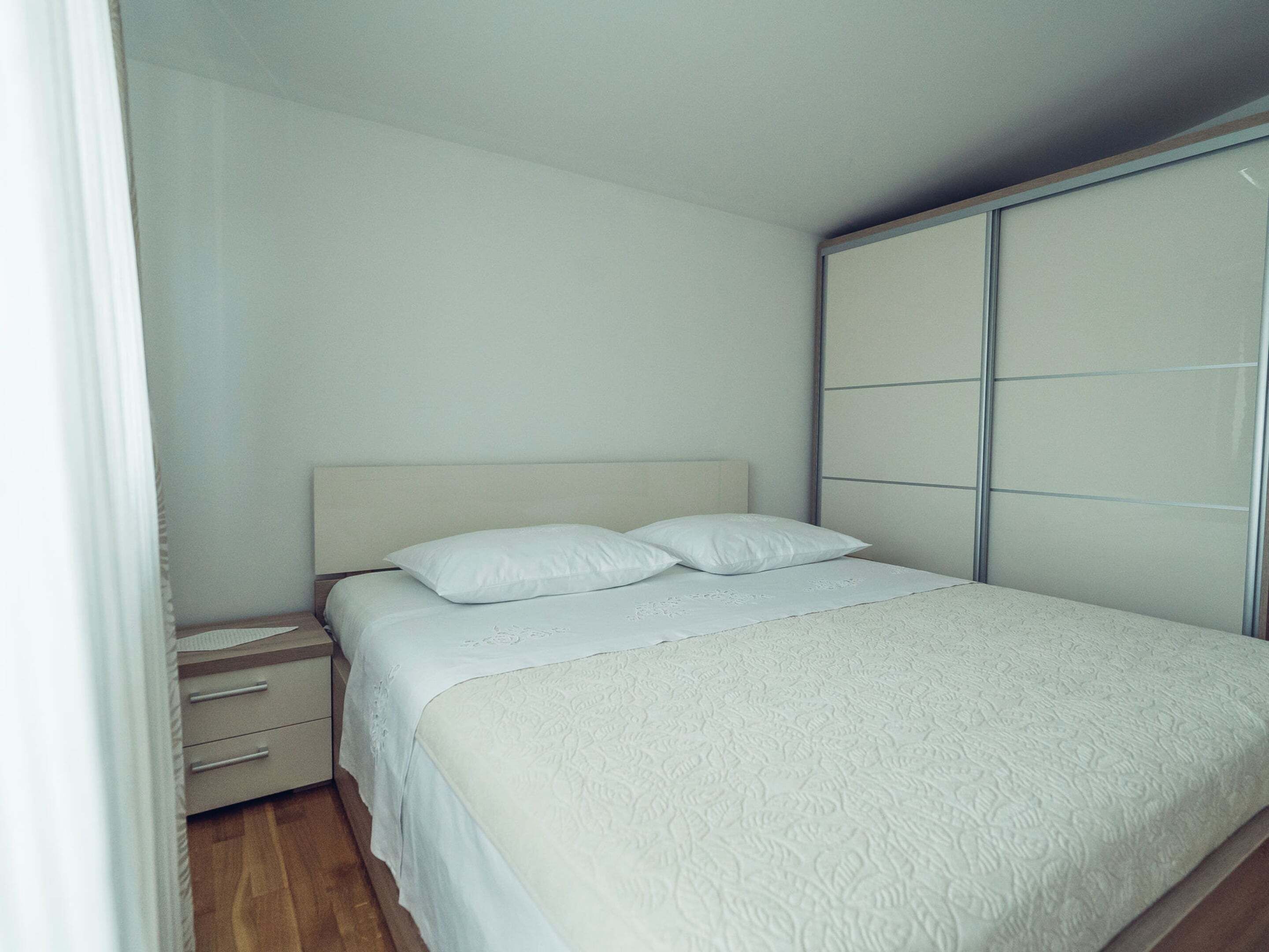 A bedroom with a bed, a nightstand, and a wardrobe.