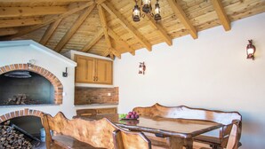 A rustic kitchen with a brick oven, wooden beams, and a wooden dining table with benches. - Holiday Home in Imotski With Pool (Imotski)
