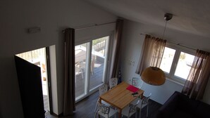 A spacious room with a wooden dining table, white chairs, a sofa, and large windows with curtains. - Modern Holiday Home With Terrace, Near the Sea (Sali)