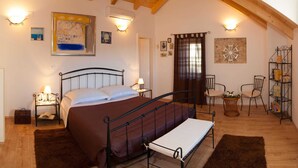 A bedroom with a bed, bedside tables, a chair, a small table with a plant, and a shelf with books and decorative items. - Modern Villa in Grohote With Pool (Solta)