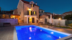 A stone house with a swimming pool, outdoor seating, and a staircase leading to the entrance. - Modern Villa in Grohote With Pool (Solta)